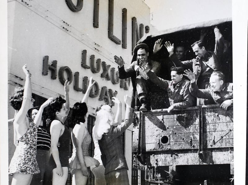 Early holidaymakers to Butlin's, in Clacton, give a cheery farewell wave to the last of the soldiers as they leave in 1946. The holiday camp had just reopened after six and a half years of military occupation during World War II.