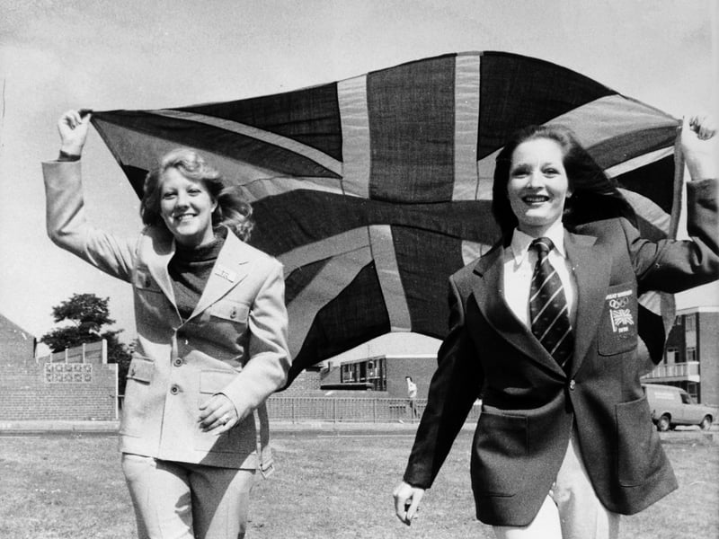 Machinists Sandra Brown and Karen Pavis pictured in June 1976. They were two of the 300 girls at Hepworths, Leeds, making outfits to be worn at the Olympic Games in Montreal by British male athletes and officials. Sandra is wearing the trendy pale blue safari suit in which the athletes would fly out to Montreal, and Karen is wearing the team's parade uniform - royal blue single breasted blazer with beige trousers.