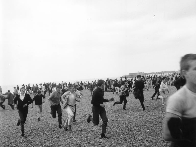 A group of Mods running along the beach at Hastings, Kent, during violence between the Mods and Rockers, in August 1964