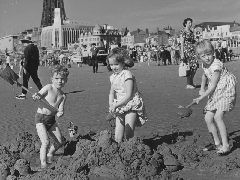Children build sandcastles on the beach at Blackpool in August 1965