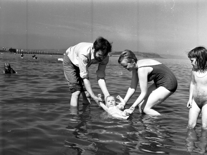 Mr and Mrs Bain dip their baby daughter into the water at Cramond, Edinburgh, in August 1970
