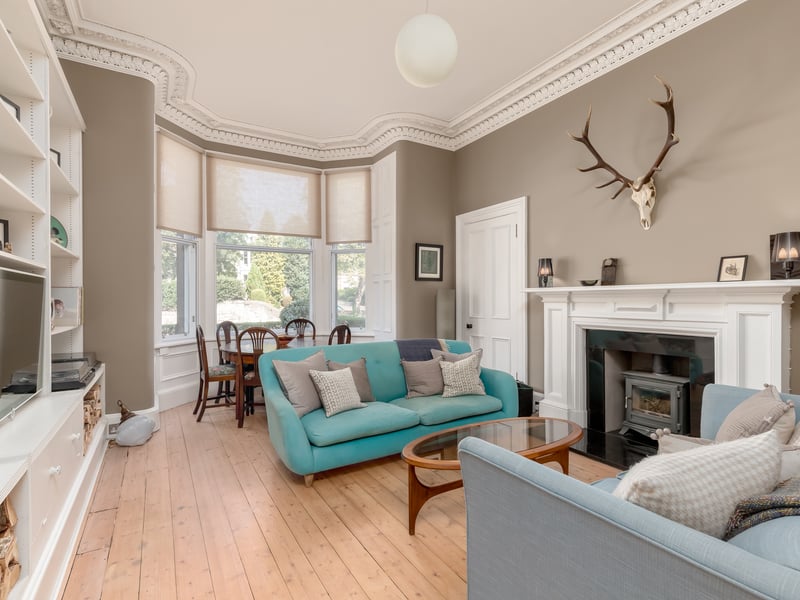 With a bright bay window, the sitting room of 2 Western Terrace retains a number of period features such as the wood-burning stove and ornate cornicing.