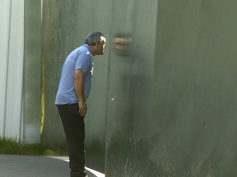 A member of the public peers through a gap in the wall of steel which surrounds the site within Roundhay Park ahead of the Robbie Williams concert, on September 7, 2006