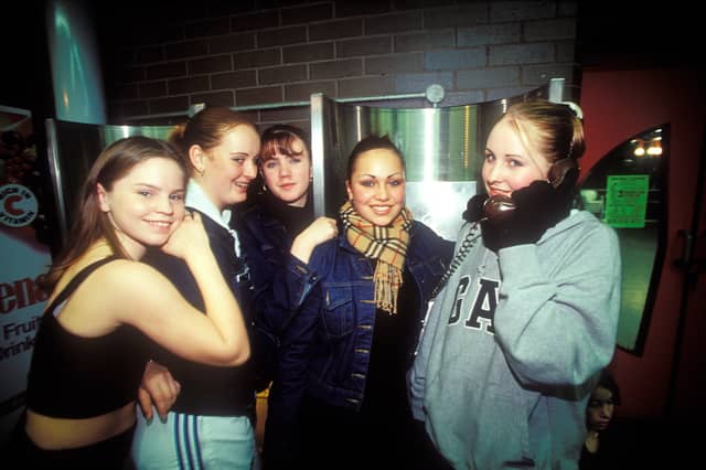 A group of girls using a payphone in 1999, before most people had mobile phones
