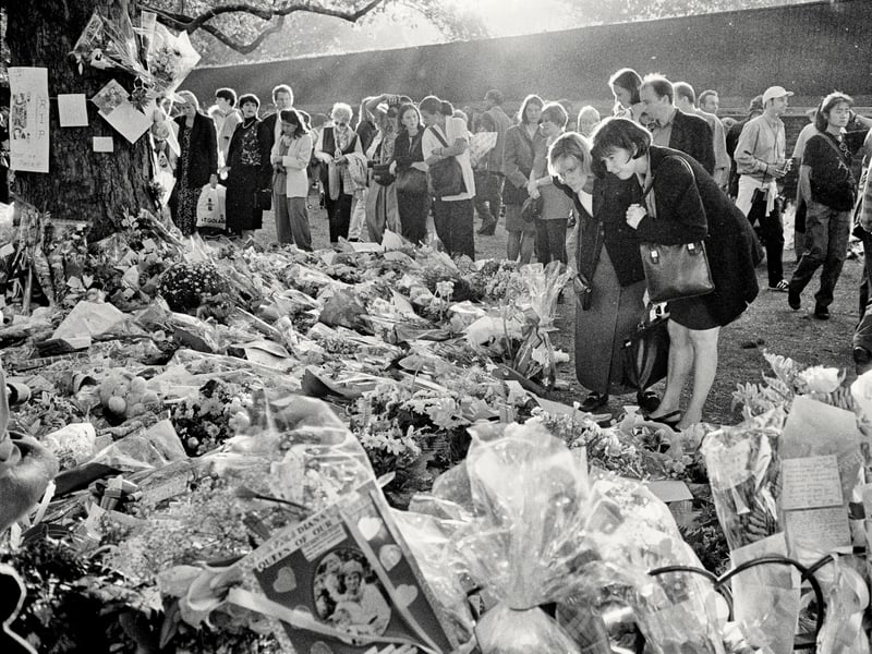 Mourners read the messages on the hundreds of bouquets of flowers lining the length of the Mall between Buckingham Palace and Whitehall, during the public funeral of Diana, Princess of Wales, on September 6, 1997