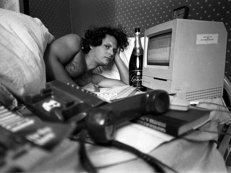 NME journalist James Brown, who co-founded the magazine Loaded in 1994, is pictured in bed with an Apple Macintosh computer, a bottle of Champagne, a phone and a Raymond Chandler novel
