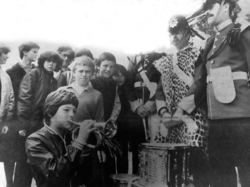 Thirteen-year-old Lisa Humphreys gets a note out of a bugle under the critical eye of members of the Corps of Drums of the Royal Hampshire Regiment during their visit to Priory School, Southsea