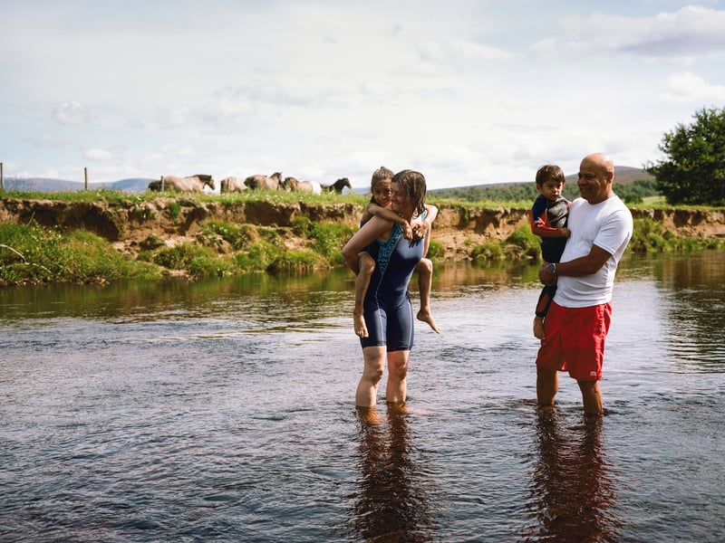 The Ali family enjoying a refreshing break from summer heat in the river near their home on the outskirts of Kingussie.