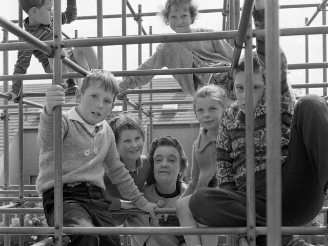 Dame Jean Roberts, Chairwoman of Cumbernauld New Town with some children on the climbing frame in a playground in 1965.