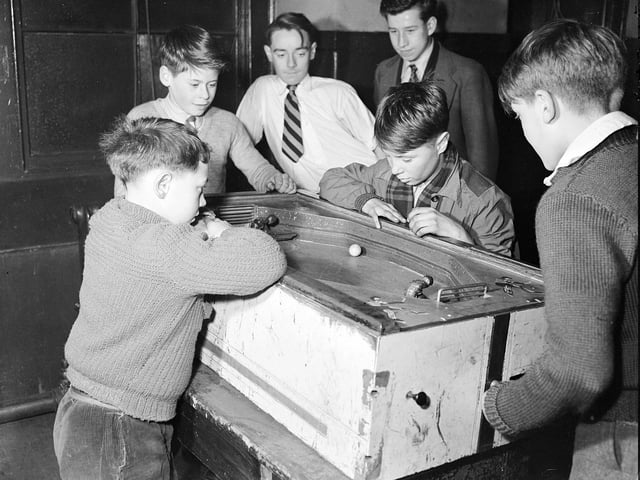 Boys playing 'mock hockey' - an early version of table football - at the United Crossroad Boys' Club in 1955.