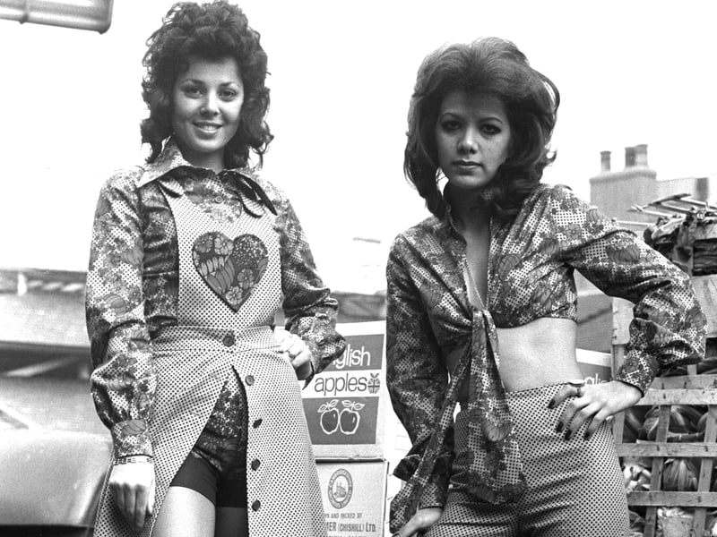 Two young women wearing 70s fashions, featuring hearts and flowers