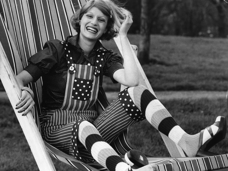 A young woman models a spotted blouse, dungarees and striped pedal pushers, in 1972