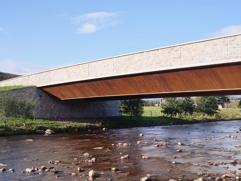 The Gairnshiel Jubilee Bridge in Glengairn provides a sleek new crossing over the River Gairn. RIAS describes the design's geometry as "slim-line" and "bold" and commends its material palette which includes recycled, locally sourced granite for the parapets and embankments and weathering steel for the primary structure, rooting the new bridge into its surroundings near the Cairngorms