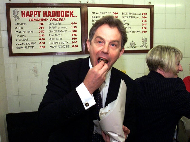 Prime Minister Tony Blair tucks into some fish and chips at the Happy Haddock restaurant in Brighouse, West Yorkshire, in May 2001. Just look at those prices on the wall behind him!