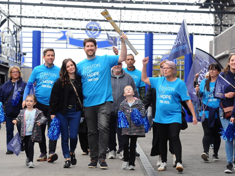 Portsmouth FC fan Daniel O'Brien carries the baton through Fratton Park with his family.