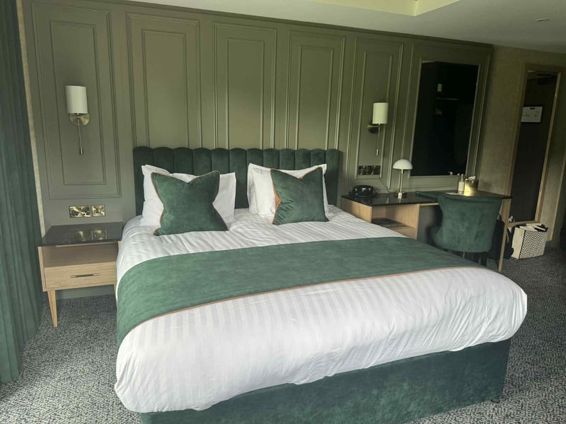 A comfortable sleep was enjoyed in this plush king-sized bed with a deep-green velvet headboard, complemented by soft suede accents.