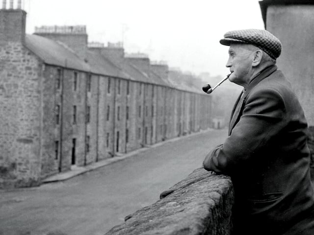 A man looks out over 18th Century tenements in New Lanark in December 1958.