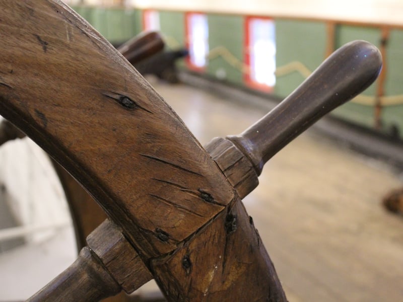 A close up of the ship's wheel on board the HMS Unicorn.