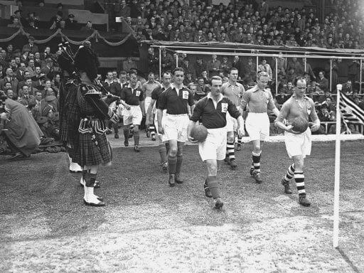 The two teams are led onto the field by their captains before the start of the game. Rest of Europe (l) are wearing dark shirts and Great Britain (r) are wearing light shirts before a crowd of 134,000 at Hampden Park.