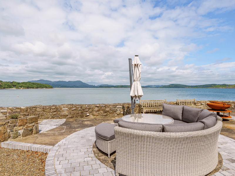 Step outside to a breath-taking terrace overlooking the sea, equipped with plenty of furniture, a crackling fire pit, and a barbecue.