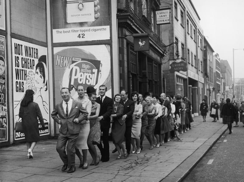 Posters advertising Persil and gas are pictured in this image from October 1964, which also shows bandleader Joe Loss introducing a Finnish version of the conga outside the Hammersmith Palais