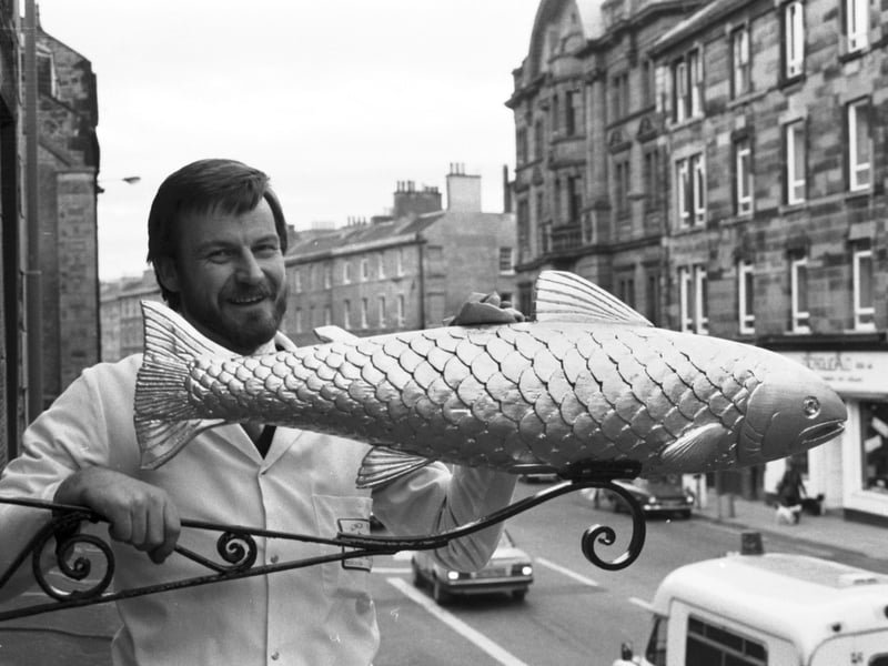 Owner Peter MacIntyre replaces the gilded salmon sign above Miller's fishmongers in Tollcross, Edinburgh, in November 1985