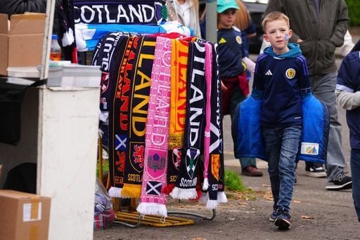 A young fan makes his way to the stadium past a fine selection of match day scarves outside the ground.