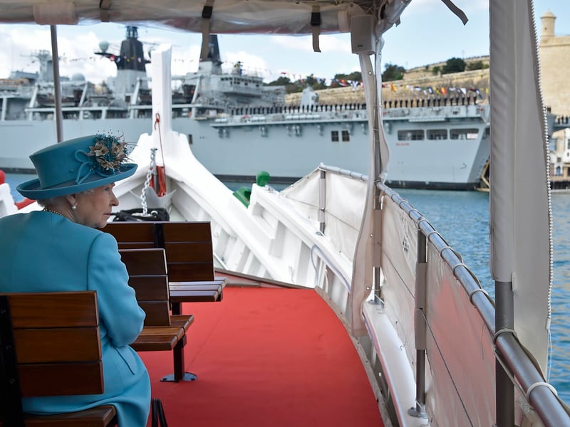 Queen Elizabeth II tours the Grand Harbour in a traditional Maltese fishing boat, with the HMS Bulwark amphibious assault ship seen in the background on November 28, 2015 in Valletta, Malta.