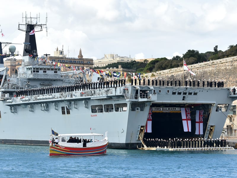 Marines of the HMS Bulwark, a ship of the Royal Navy, greet Queen Elizabeth II during her boat trip on a traditional Maltese boat around the Mediterranean island of Malta on November 28, 2015