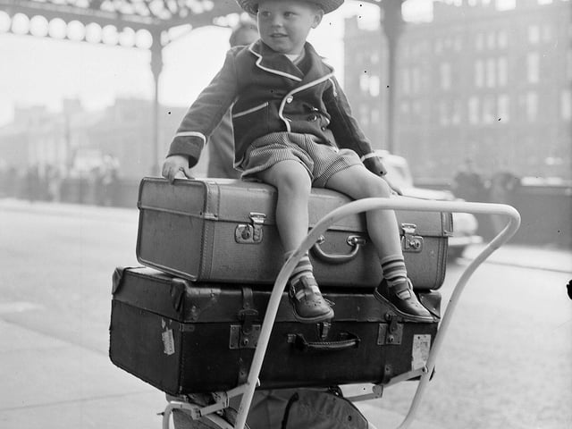Three-year-old Paul Flannigan sits on top of luggage ready to head off for his Glasgow Fair Holidays from the city's Central Station.