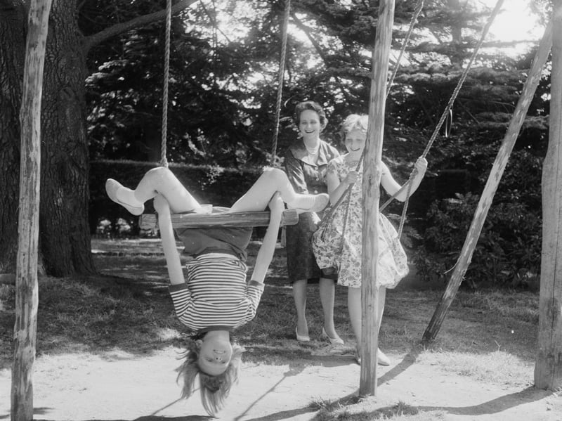 Eight-year-old Lucy de Lisle hangs upside down from a garden swing, watched by her mother, Lady de Lisle, and sister Anne, in July 1961. The family were about to move from their home in Kent to Australia, where Lord de Lisle was to take up his post as Governor-General of Australia.