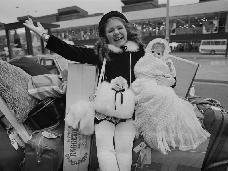 Actress, dancer and entertainer Bonnie Langford sits on a stack of suitcases with her dolls in January 1975