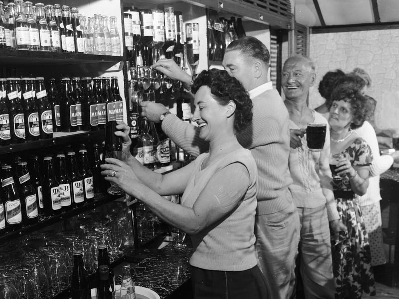 Customers help themselves to bottles at a self-service pub on a caravan park in September 1962
