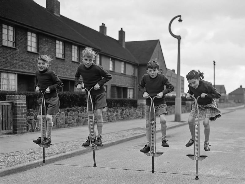 The Taylor quads from Edmonton in London bounce down the street on their pogo sticks in 1958