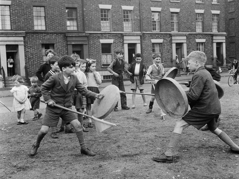 Children using dustbin lids and broomsticks as shields and lances during a game of knights in Liverpool in May 1956