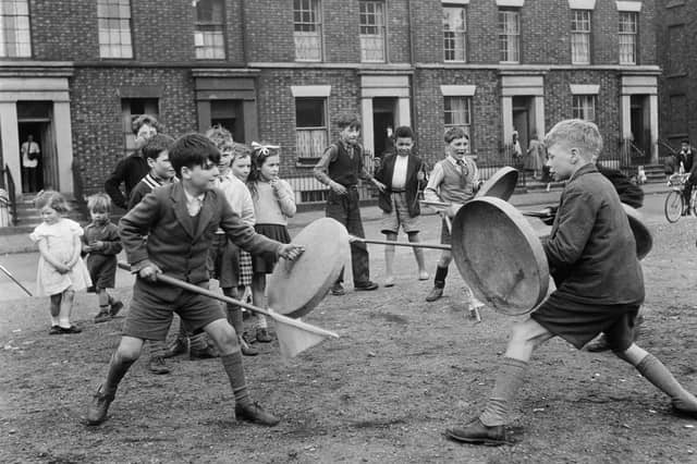 Children using dustbin lids and broomsticks as shields and lances during a game of knights in Liverpool in May 1956