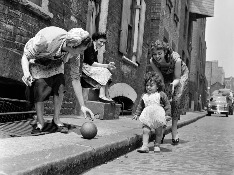 Television actress Catherine Fuller makes friends with a toddler in the street in London's East End in June 1956