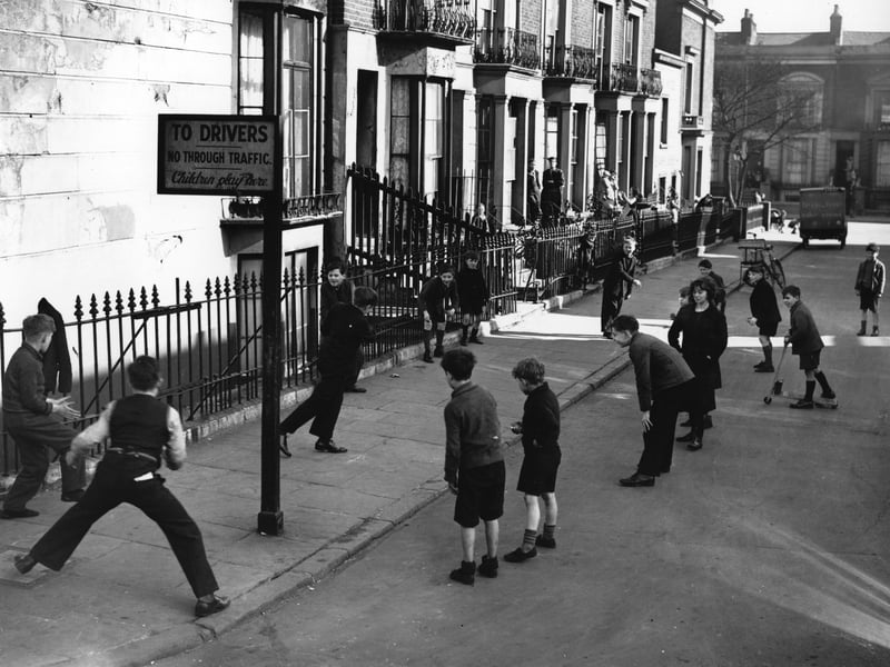 Children playing in the street, beneath a sign saying: "No through traffic. Children play here."