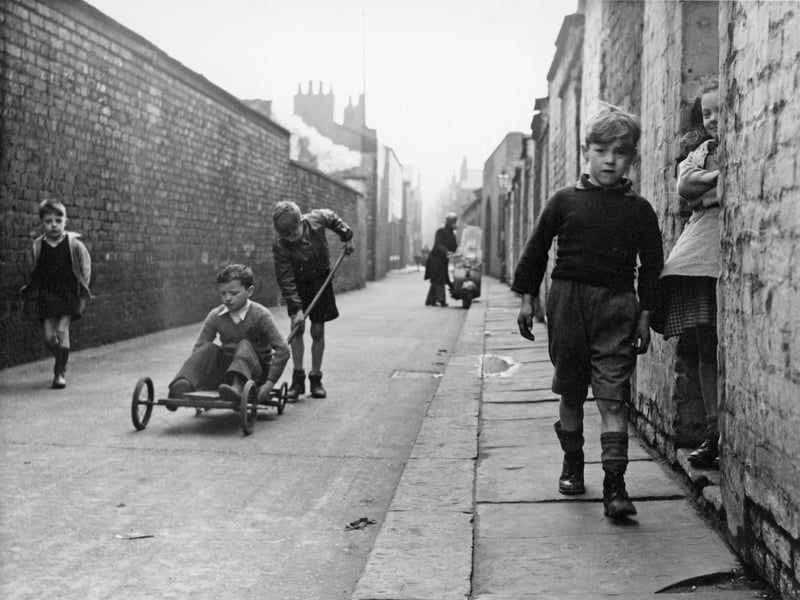 Children on a street in Salford, including a youngster on a go-kart, in 1957