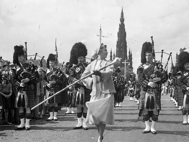 American actress Vera-Ellen leads a pipe band down Princes Street whilst filming the 1956 movie 'Let's Be Happy'.