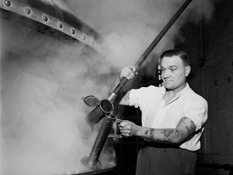 A worker takes a beer sample from a vat at the Watney, Combe, Reid & Co Brewery in Pimlico, London, in March 1957