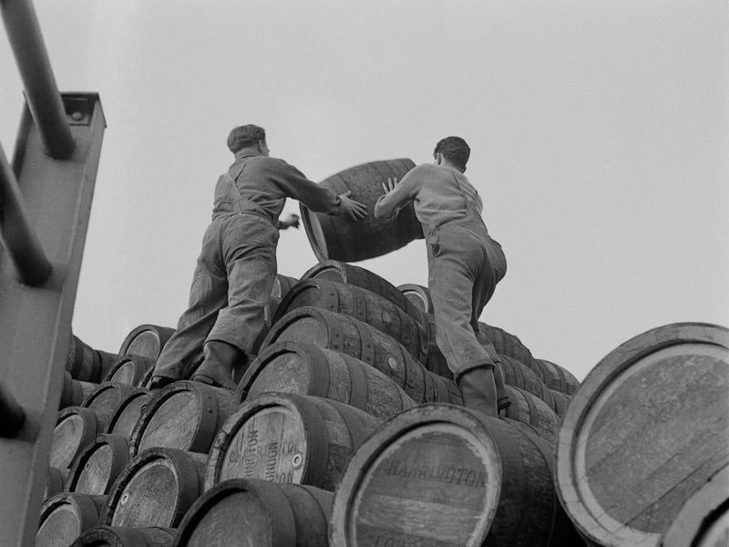 Two men carrying a barrel to the top of a stack at Charrington's Anchor Brewery, Mile End Road, London, in November 1957