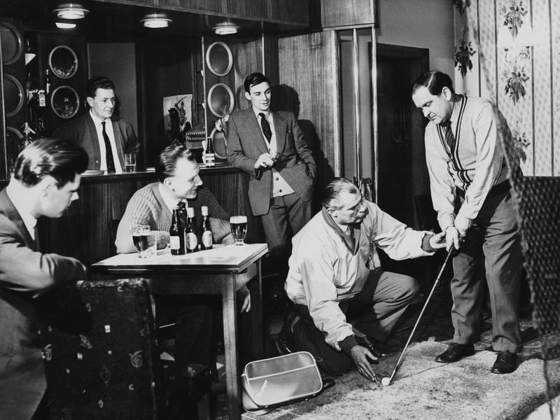 Local golfer Bob Midwood shows Jack Richardson how to hold a golf club in the cocktail bar of the Staincross Hotel, Barnsley, Yorkshire, in February 1962