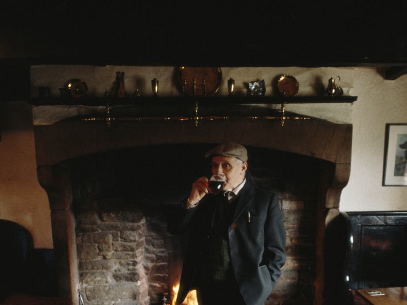 A customer enjoys a quiet pint in front of the fire at the Forresters Arms pub in the rural village of Carlton, North Yorkshire, in April 1982