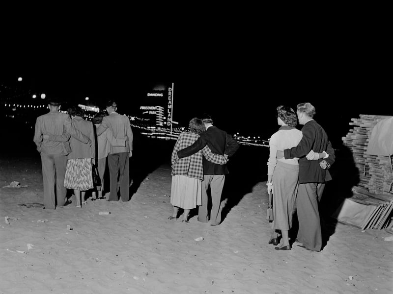Four couples walking along Margate beach, in Kent, at night in July 1952