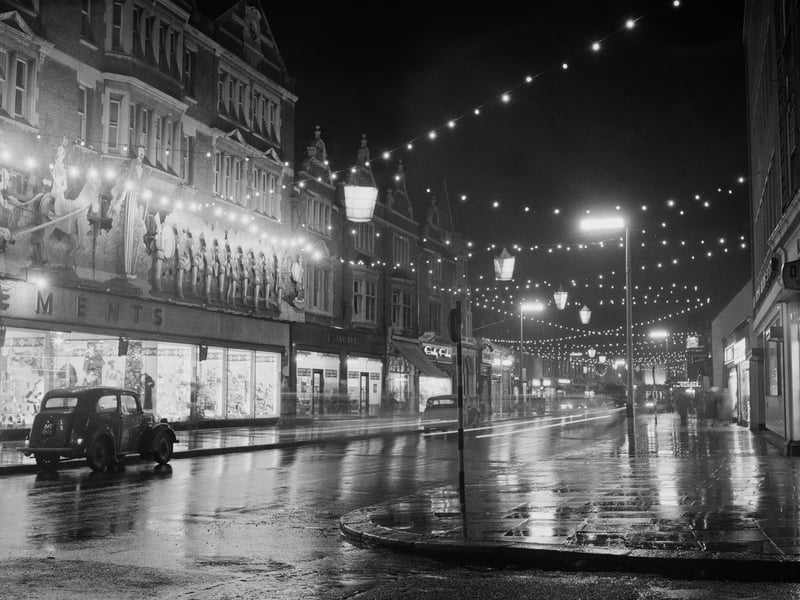 Watford High Street at night in December 1959, showing the wet street and pavements lit up by street lights and Christmas illuminations