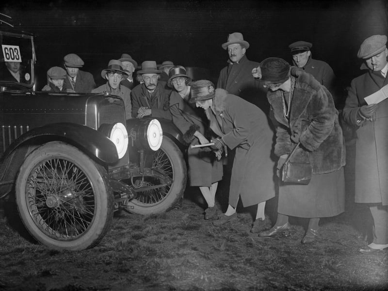 Motorists inspect a device designed to reduce dazzle from a vehicle's headlights, fitted here on an Austin, in 1925