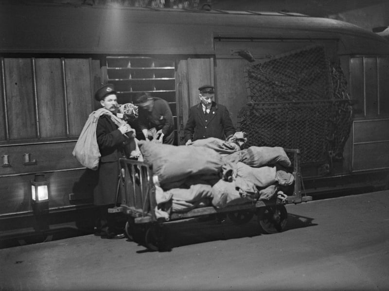 Railwaymen load mail sacks onto a train at King's Cross station, London, at night in March 1930