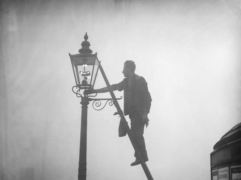 A lamp lighter at work in Finsbury Park, London, in October 1935