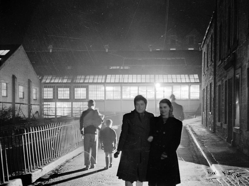 Workers walking arm-in-arm outside the Wilson and Glenny Mill at Hawick in the Scottish Borders, where tartan and tweed are made, in 1950